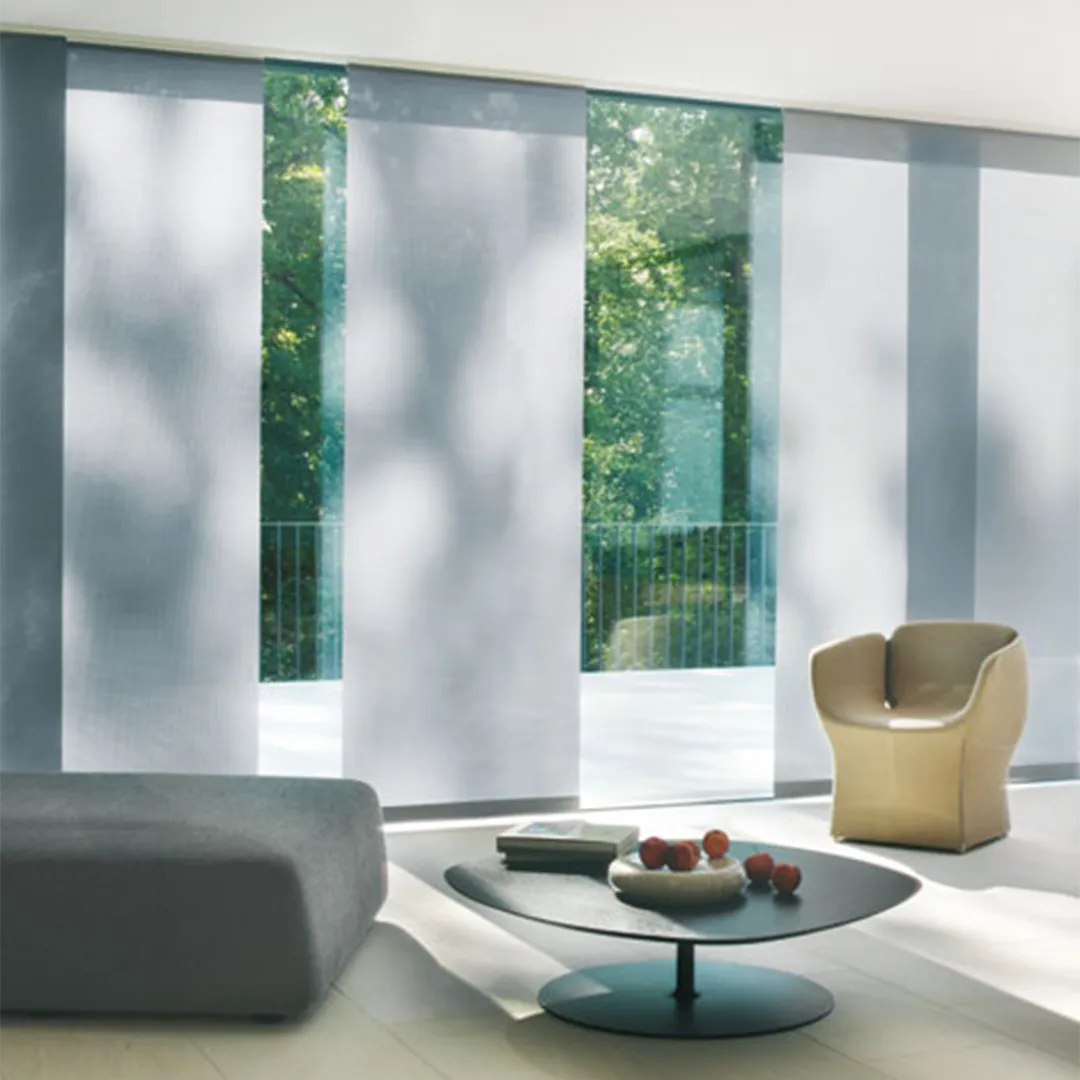 Modernes Wohnzimmer mit großen Fenstern, Flächenvorhänge, grauem Sofa und stilvollem Sessel.